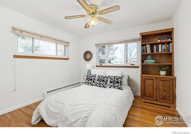 bedroom featuring light wood finished floors, baseboards, baseboard heating, and ceiling fan