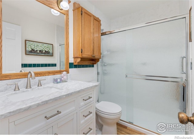 full bathroom with vanity, toilet, a shower stall, and wood finished floors