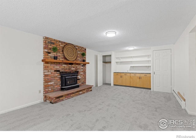 unfurnished living room featuring a wood stove, carpet, a textured ceiling, and a baseboard radiator