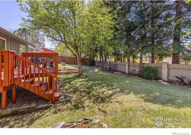 view of yard featuring a deck, a fenced backyard, and stairs