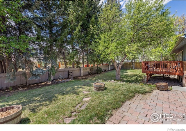 view of yard featuring an outdoor fire pit, a deck, a patio area, and a fenced backyard