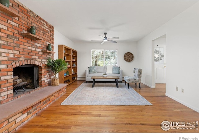 living area with a ceiling fan, baseboards, a fireplace, and wood finished floors