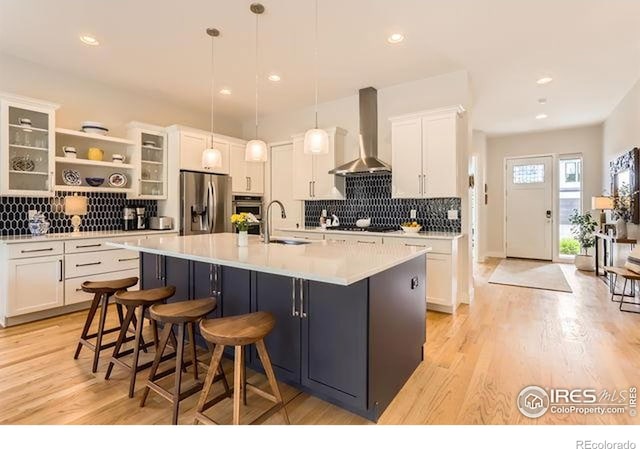 kitchen with white cabinetry, wall chimney exhaust hood, stainless steel appliances, and a sink