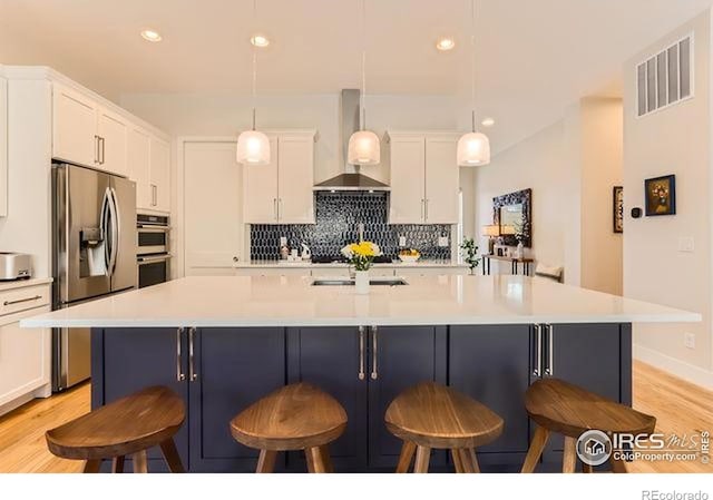 kitchen featuring white cabinetry, wall chimney range hood, visible vents, and appliances with stainless steel finishes