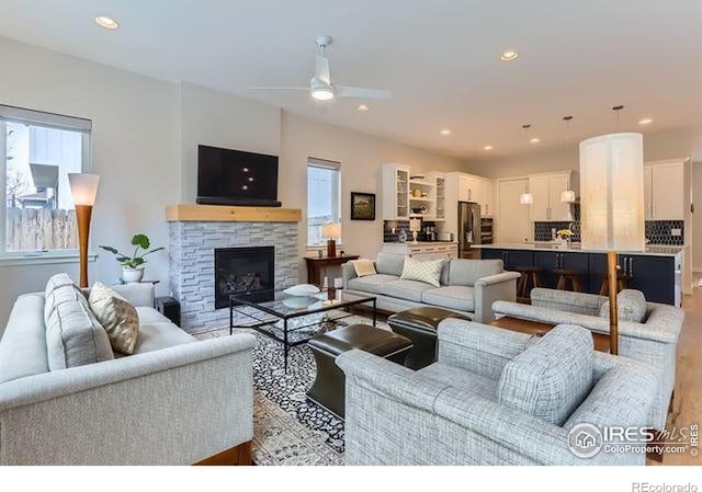 living area featuring a ceiling fan, light wood finished floors, a fireplace, and recessed lighting