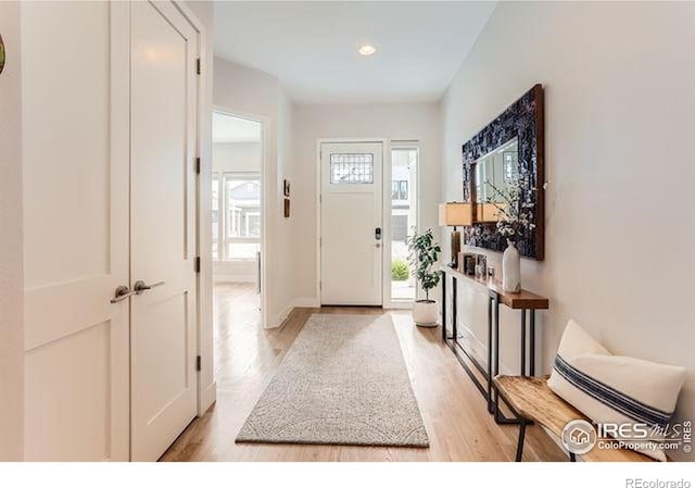 foyer entrance featuring baseboards, light wood-style flooring, and recessed lighting