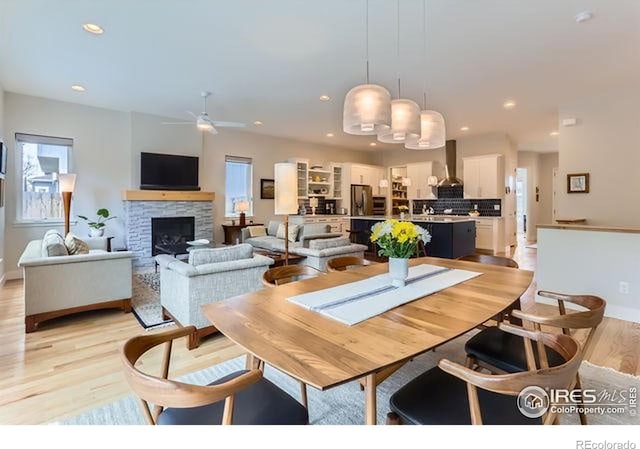 dining space with recessed lighting, baseboards, light wood finished floors, ceiling fan, and a fireplace
