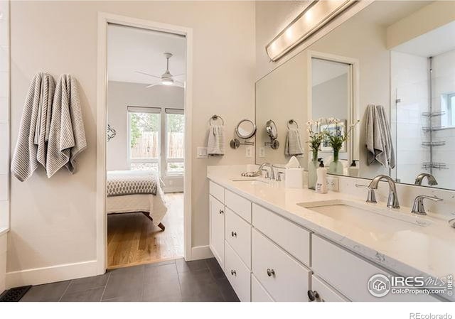 bathroom featuring a ceiling fan, ensuite bathroom, a sink, and baseboards