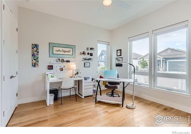 office area featuring baseboards, light wood-style flooring, and a ceiling fan