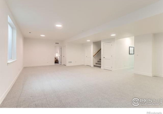 basement with stairway, light colored carpet, baseboards, and recessed lighting