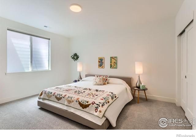 bedroom with carpet flooring, a closet, visible vents, and baseboards