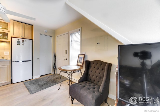 sitting room featuring electric panel, baseboards, and light wood-style floors