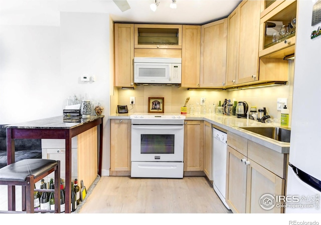 kitchen featuring white appliances, light wood finished floors, backsplash, glass insert cabinets, and light brown cabinets