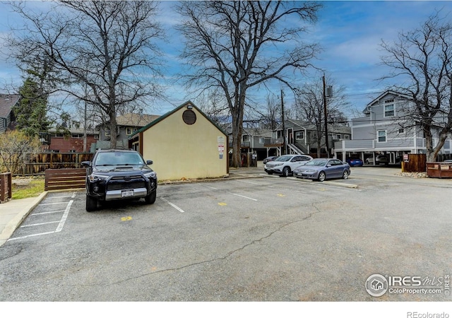 uncovered parking lot featuring a residential view and fence