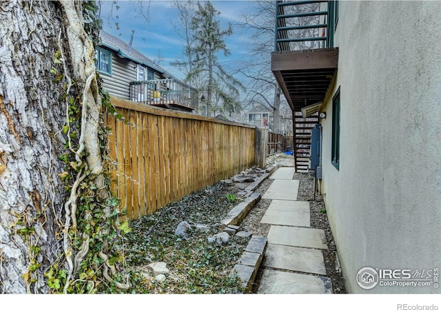 view of side of home featuring stairway, fence, stucco siding, and a balcony