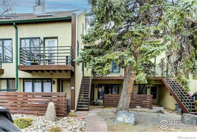 back of house featuring stucco siding, stairway, and a balcony