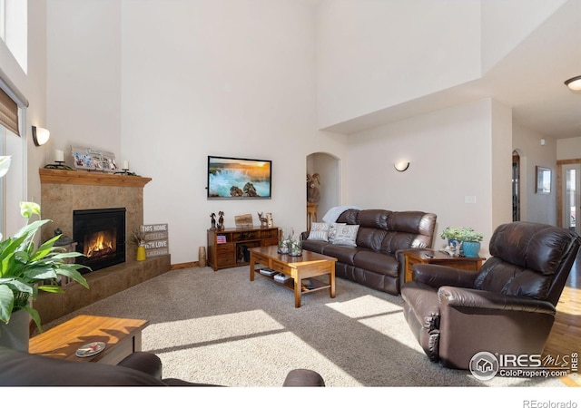 7084 Sumner St, Wellington, CO 80549 - carpeted living room featuring a high ceiling, arched walkways, and a tile fireplace