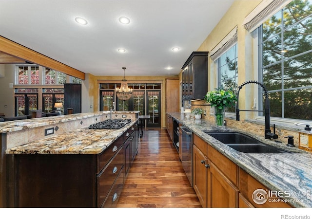 14582 Homestead Pl, Broomfield, CO 80023 - kitchen with a sink, gas stovetop, a chandelier, wood finished floors, and light stone countertops