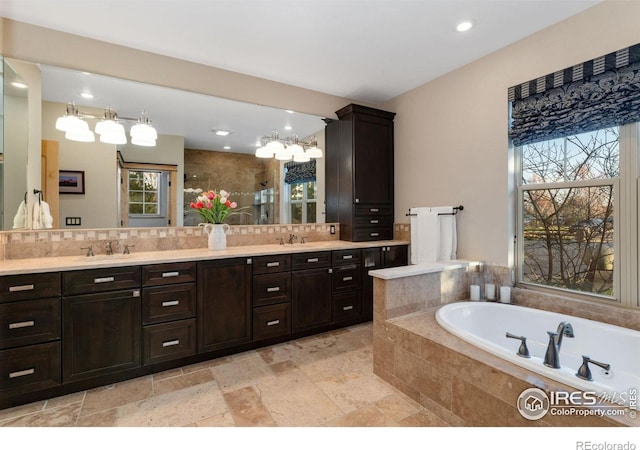 14582 Homestead Pl, Broomfield, CO 80023 - full bath with healthy amount of natural light, tasteful backsplash, a bath, double vanity, and recessed lighting