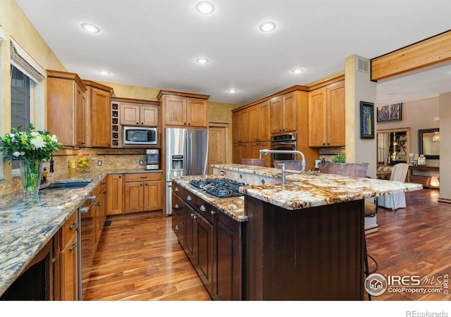 14582 Homestead Pl, Broomfield, CO 80023 - kitchen featuring stainless steel appliances, a kitchen bar, wood finished floors, a sink, and recessed lighting