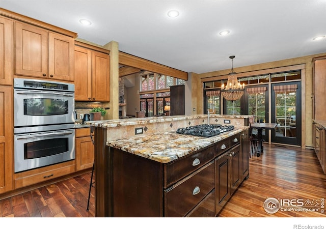14582 Homestead Pl, Broomfield, CO 80023 - kitchen featuring stainless steel double oven, gas cooktop, dark wood finished floors, a chandelier, and a kitchen island