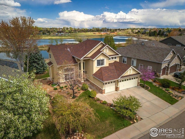 view of front facade with driveway, stucco siding, a water view, and an attached garage