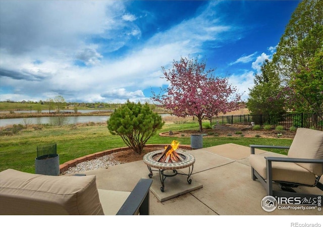 view of patio with an outdoor fire pit, a water view, and fence