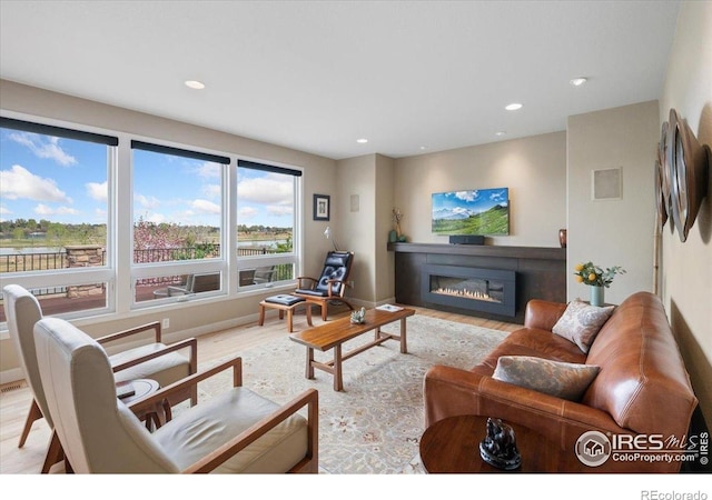 living room featuring a glass covered fireplace, recessed lighting, and wood finished floors