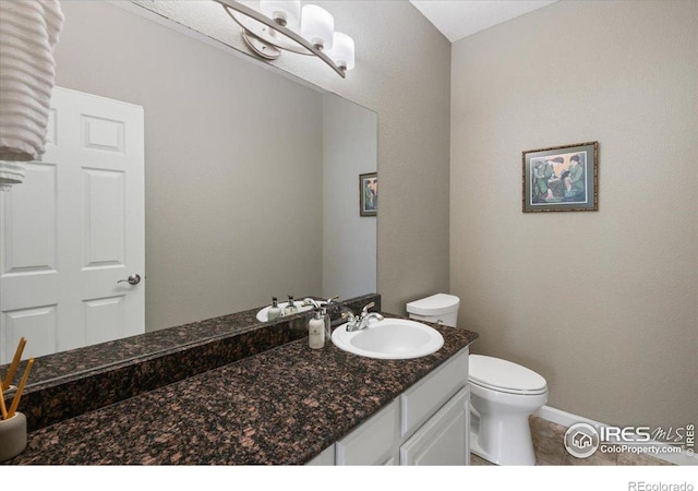 bathroom featuring vanity, toilet, baseboards, and tile patterned flooring