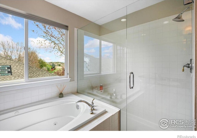 full bathroom featuring a jetted tub and a shower stall
