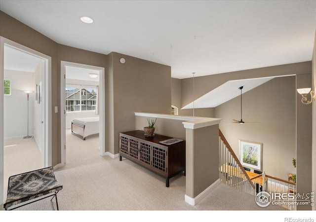 hall featuring carpet, baseboards, an upstairs landing, and a wealth of natural light