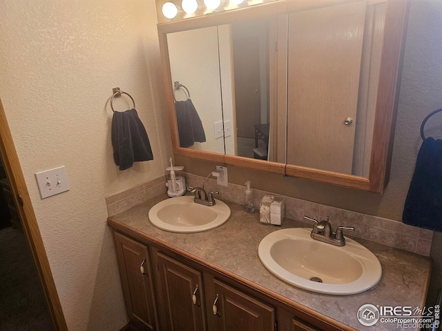 bathroom with a sink, double vanity, and a textured wall