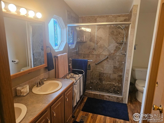 full bath with toilet, wood finished floors, a sink, and a shower stall