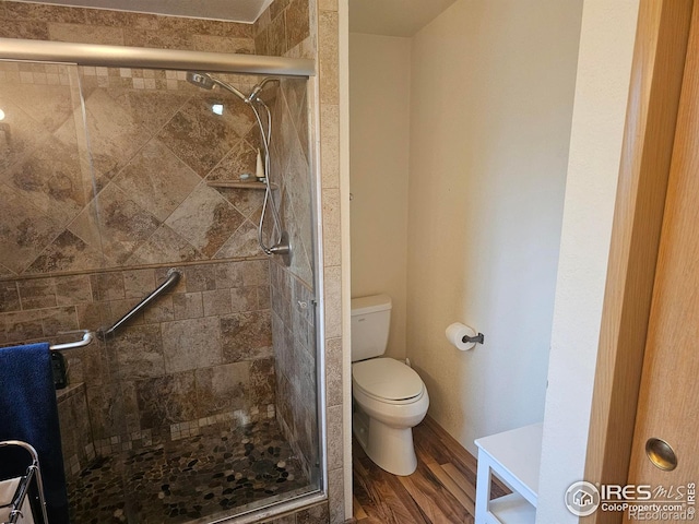 bathroom with a stall shower, toilet, and wood finished floors