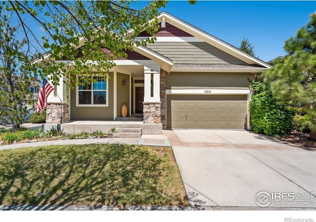 craftsman-style home featuring covered porch, an attached garage, stone siding, and driveway