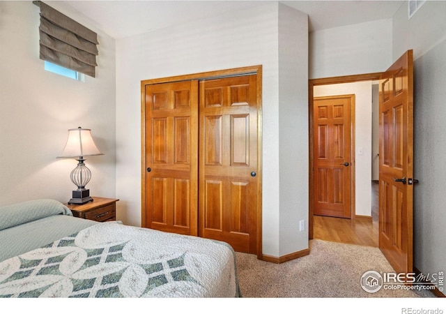carpeted bedroom with a closet, visible vents, and baseboards
