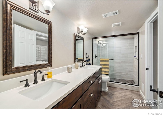 bathroom with a stall shower, visible vents, and a sink