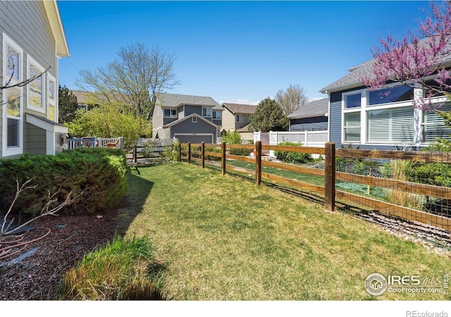 view of yard featuring a residential view, a garage, and fence