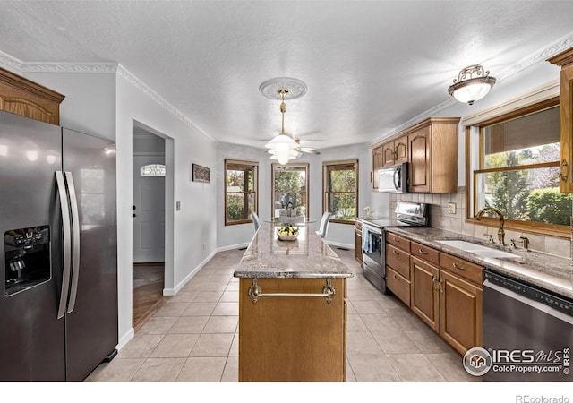 kitchen featuring light tile patterned floors, a sink, crown molding, a kitchen island, and appliances with stainless steel finishes