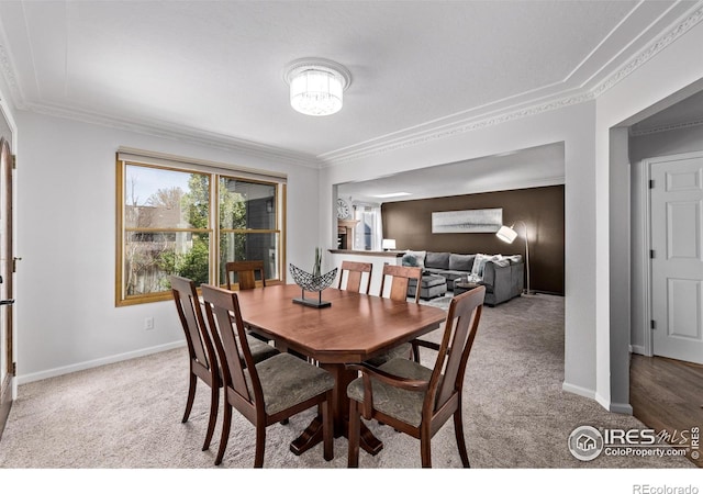 carpeted dining area featuring crown molding and baseboards