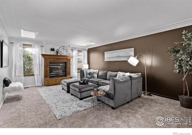living area featuring carpet flooring, crown molding, baseboards, and a glass covered fireplace