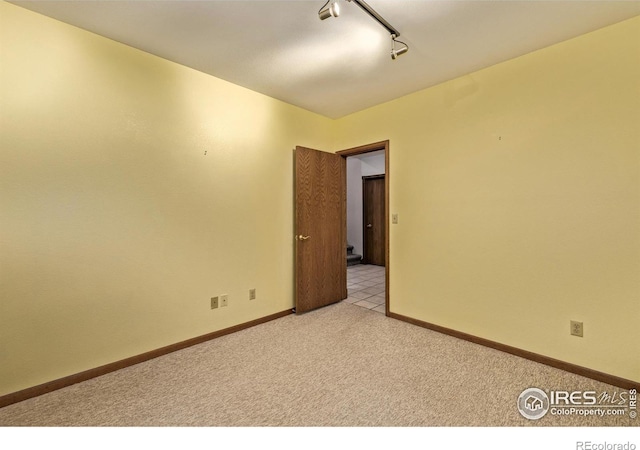 unfurnished room with baseboards, light carpet, and track lighting