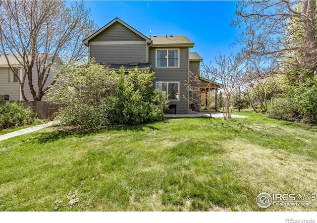 rear view of property featuring a yard, fence, and a patio area