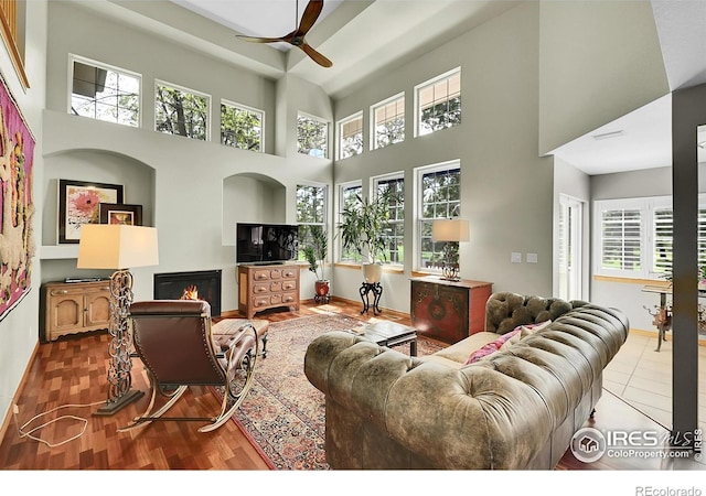 2206 Eagles Nest Dr, Lafayette, CO 80026 - living area with wood finished floors, a towering ceiling, a ceiling fan, a lit fireplace, and baseboards
