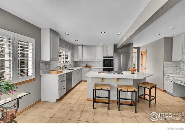 2206 Eagles Nest Dr, Lafayette, CO 80026 - kitchen featuring stainless steel appliances, a sink, decorative backsplash, a kitchen island, and light countertops
