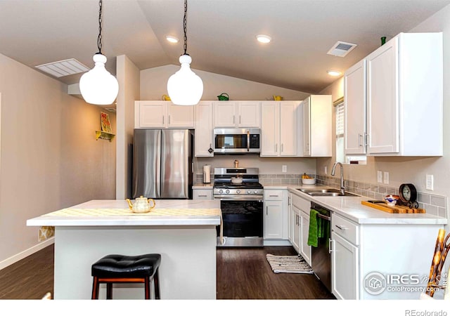 506 Bobcat Ct, Wiggins, CO 80654 - kitchen with stainless steel appliances, a sink, dark wood finished floors, vaulted ceiling, and white cabinets