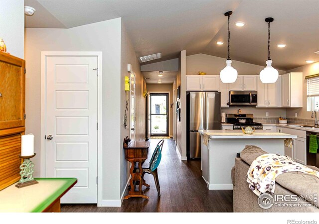 506 Bobcat Ct, Wiggins, CO 80654 - kitchen featuring appliances with stainless steel finishes, vaulted ceiling, a center island, dark wood-type flooring, and light countertops