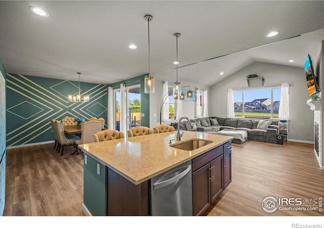 kitchen with a sink, a chandelier, dishwasher, open floor plan, and wood finished floors
