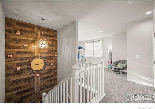 corridor featuring an upstairs landing, carpet, a chandelier, wooden walls, and recessed lighting