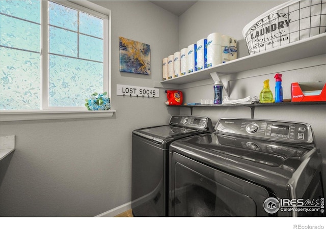 clothes washing area with washer and dryer and baseboards